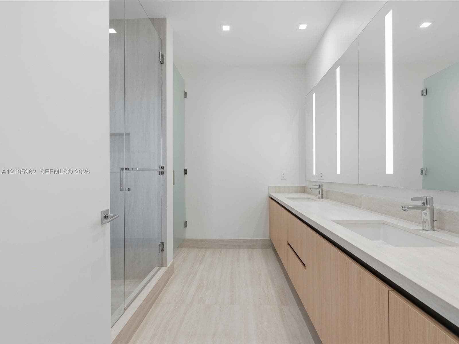 Dual-vanity cabinet with wood-finish cabinetry, solid-surface countertops, integrated full-length mirrors with LED lighting, and walk-in shower with glass enclosure