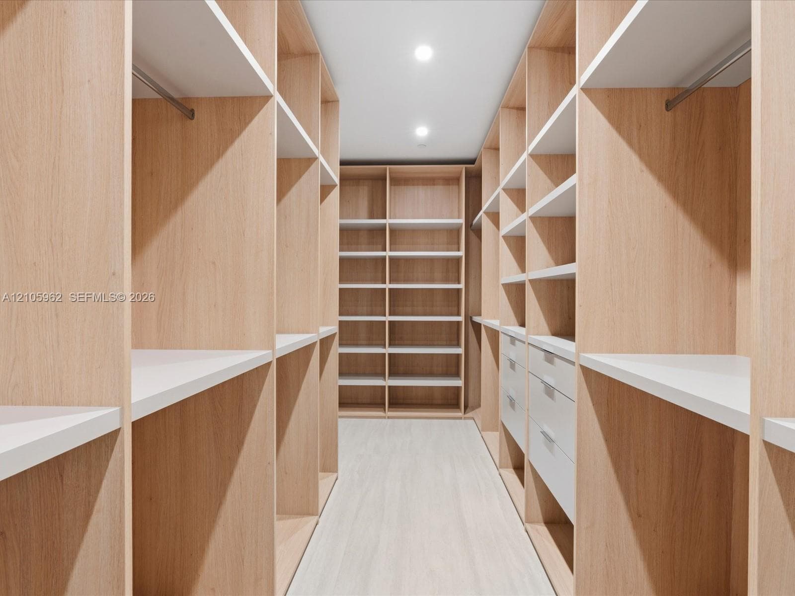 Custom closet featuring light-toned wood cabinetry, built-in shelving, integrated hanging rods, and soft-close drawer storage