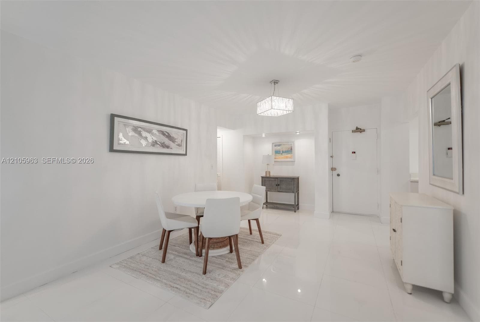 Polished white flooring, recessed accent lighting in a dedicated alcove, and a decorative drum-style chandelier