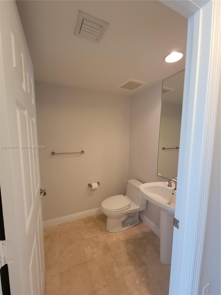 Powder room featuring a pedestal sink, polished stone flooring, recessed lighting, and a wall-mounted mirror