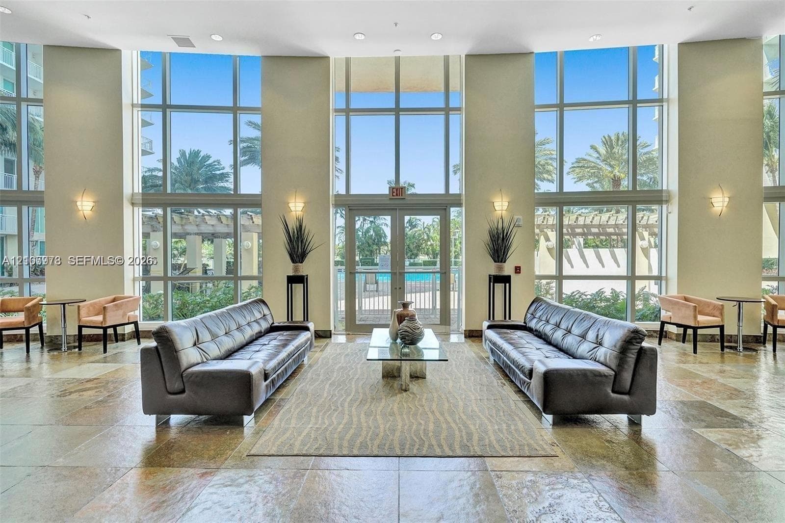 Double-height floor-to-ceiling windows, polished stone flooring, and recessed ceiling lighting