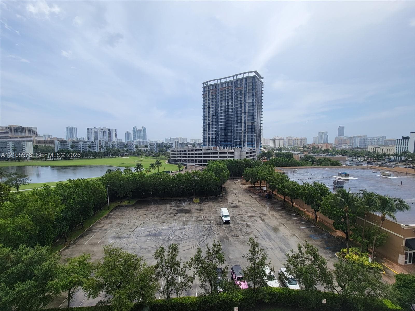 High-rise urban perspective featuring a panoramic cityscape, surrounding green space, and a large body of water