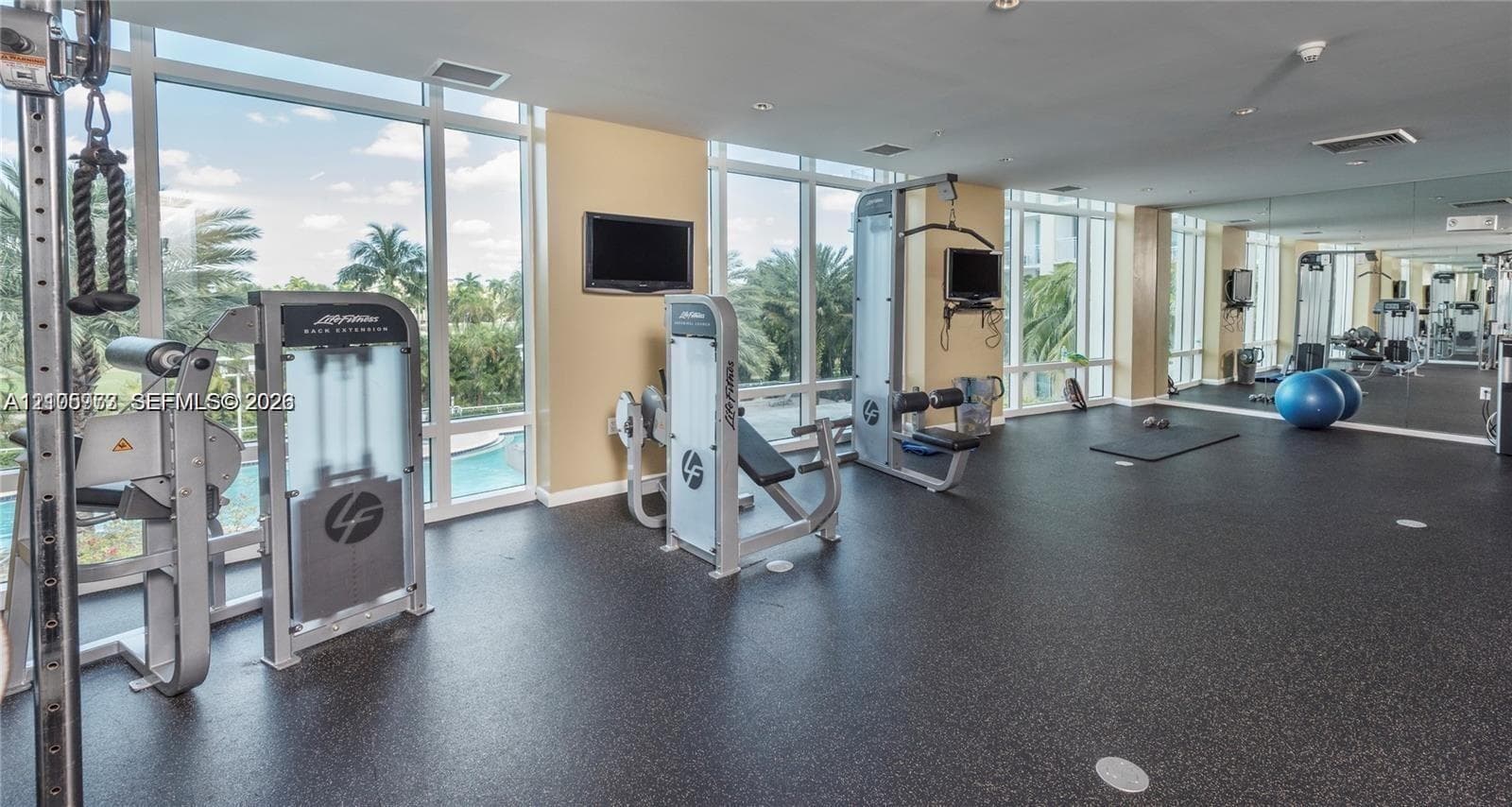 Fitness center featuring floor-to-ceiling windows, rubberized flooring, and wall-to-wall mirrors