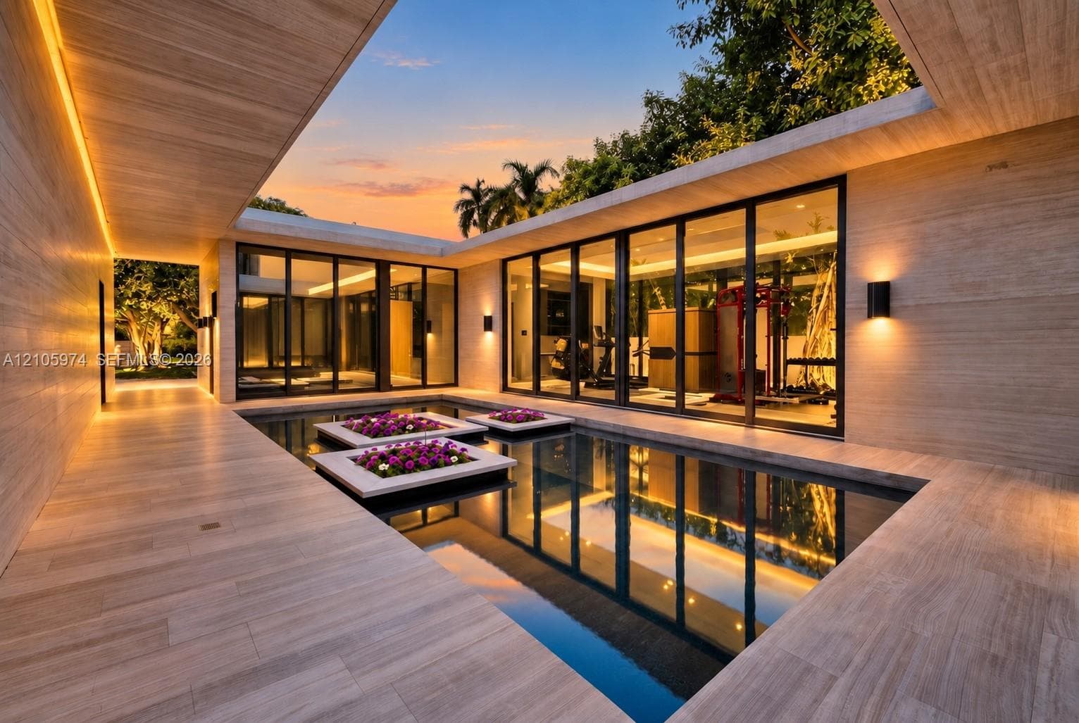 Central courtyard featuring a reflecting pool with integrated planters, floor-to-ceiling glass panel walls, natural stone-finish decking, and recessed perimeter lighting