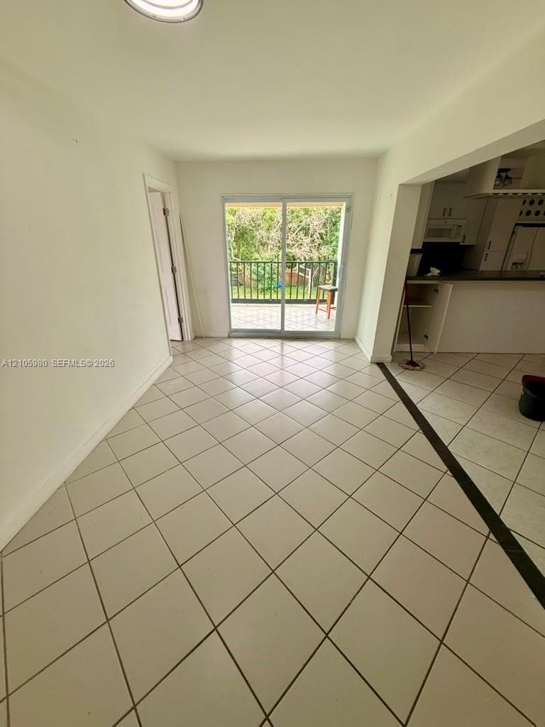 Tile flooring laid in a diagonal pattern, sliding glass door, and a private balcony with metal railing