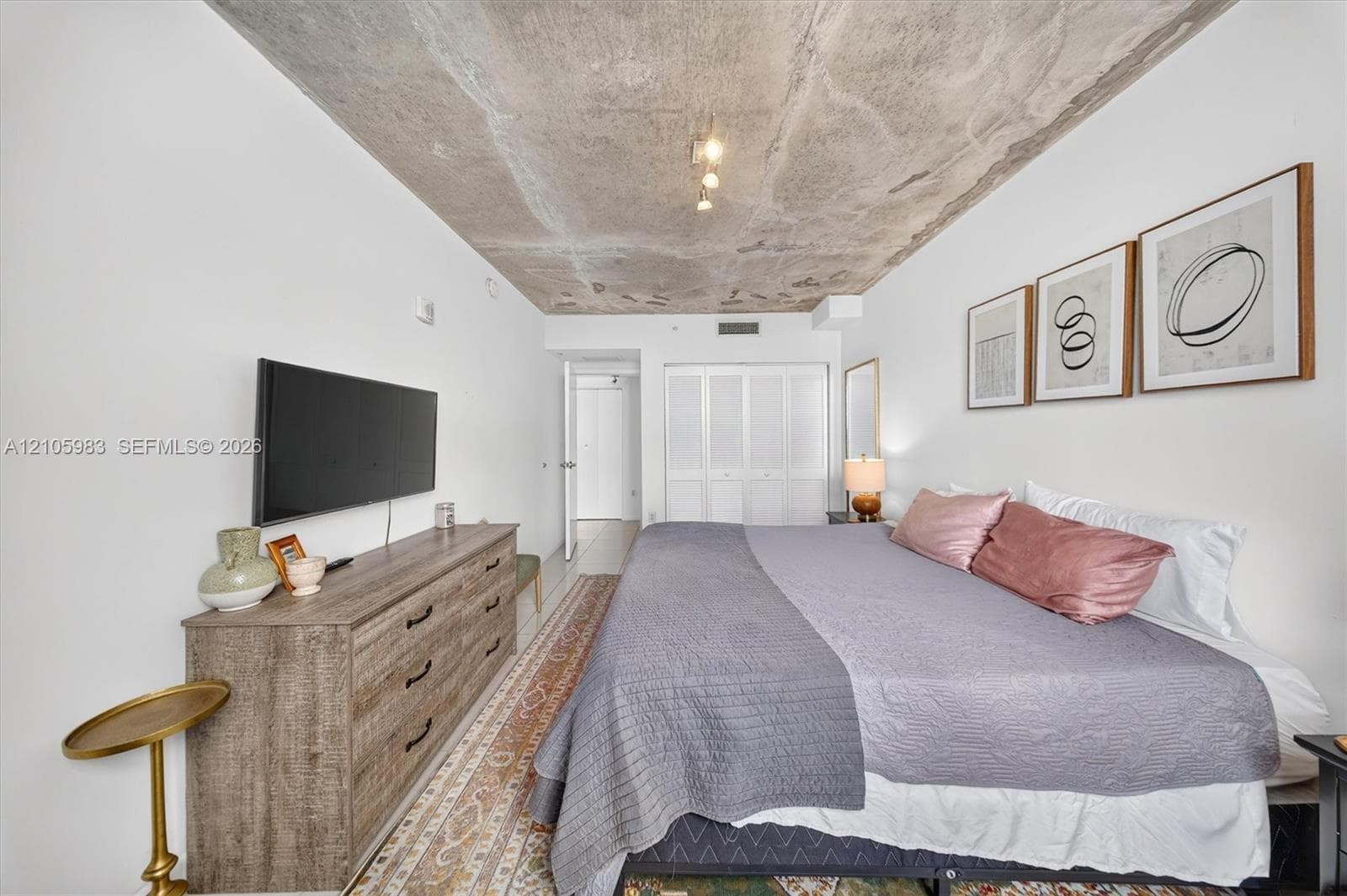 Exposed concrete ceiling and white walls featuring built-in multi-panel closet doors and mounted ceiling lighting