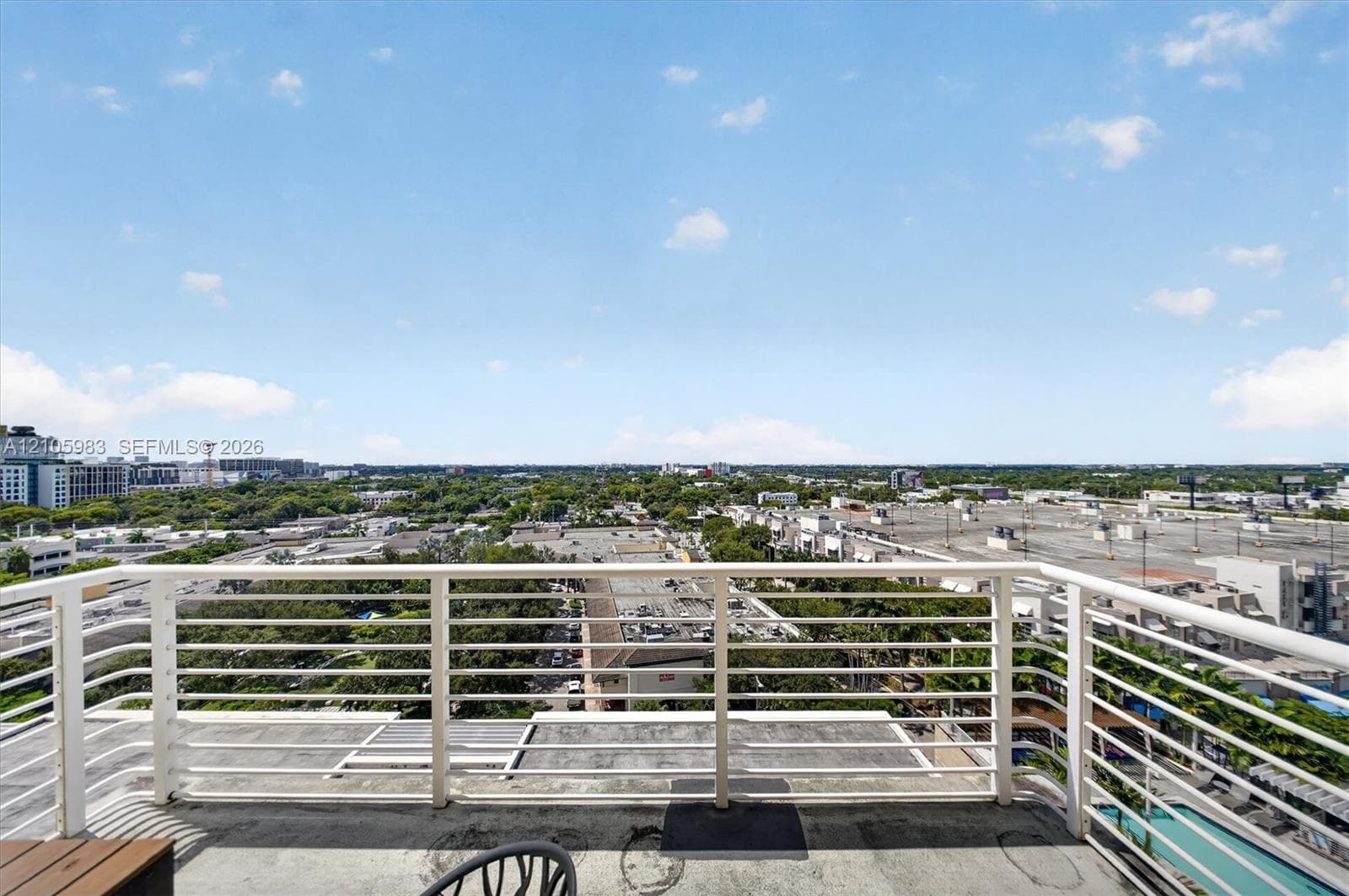 Private outdoor balcony featuring a white metal horizontal rail system and concrete flooring
