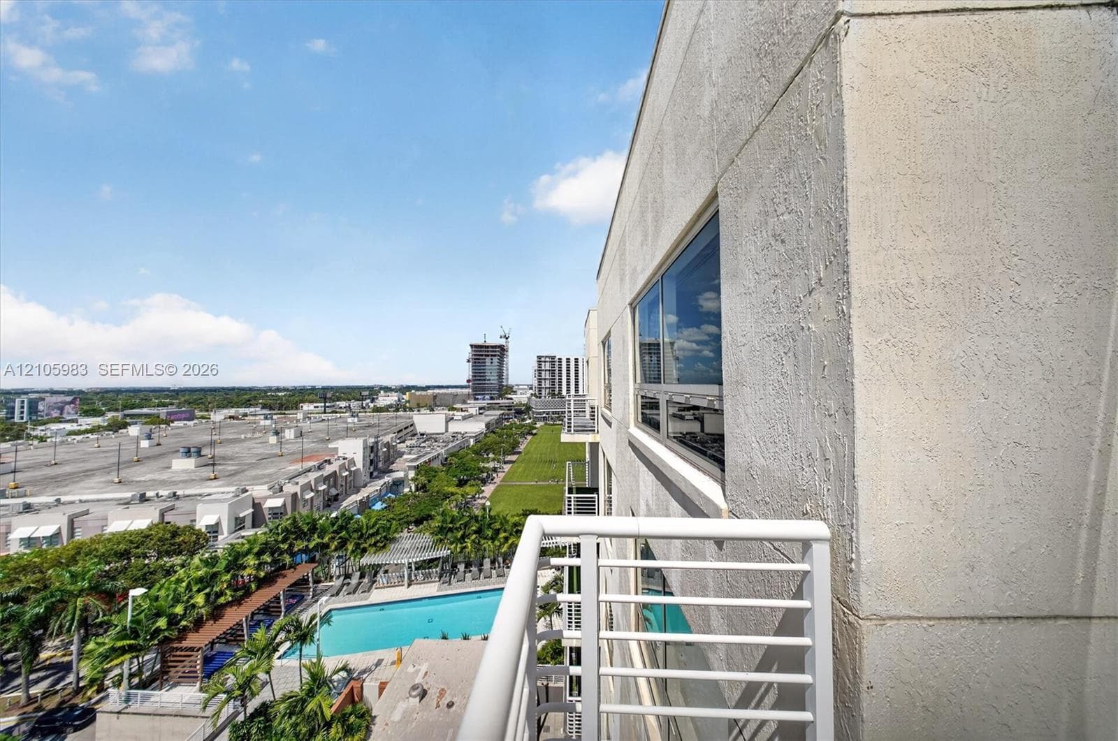 Exterior balcony featuring a metal railing, smooth stucco facade, and large window