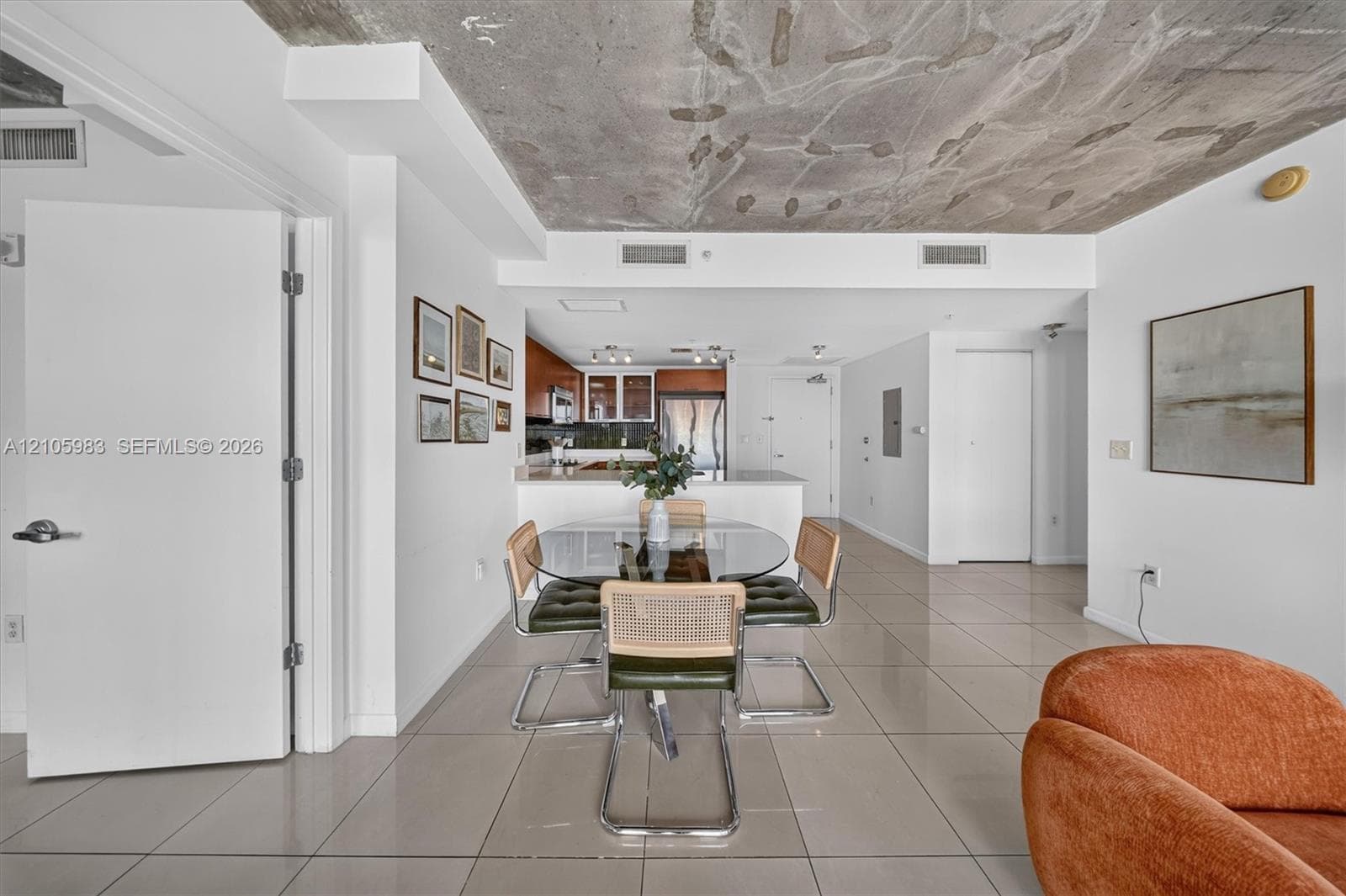 Open-concept living space featuring exposed concrete ceilings and large-format tile flooring
