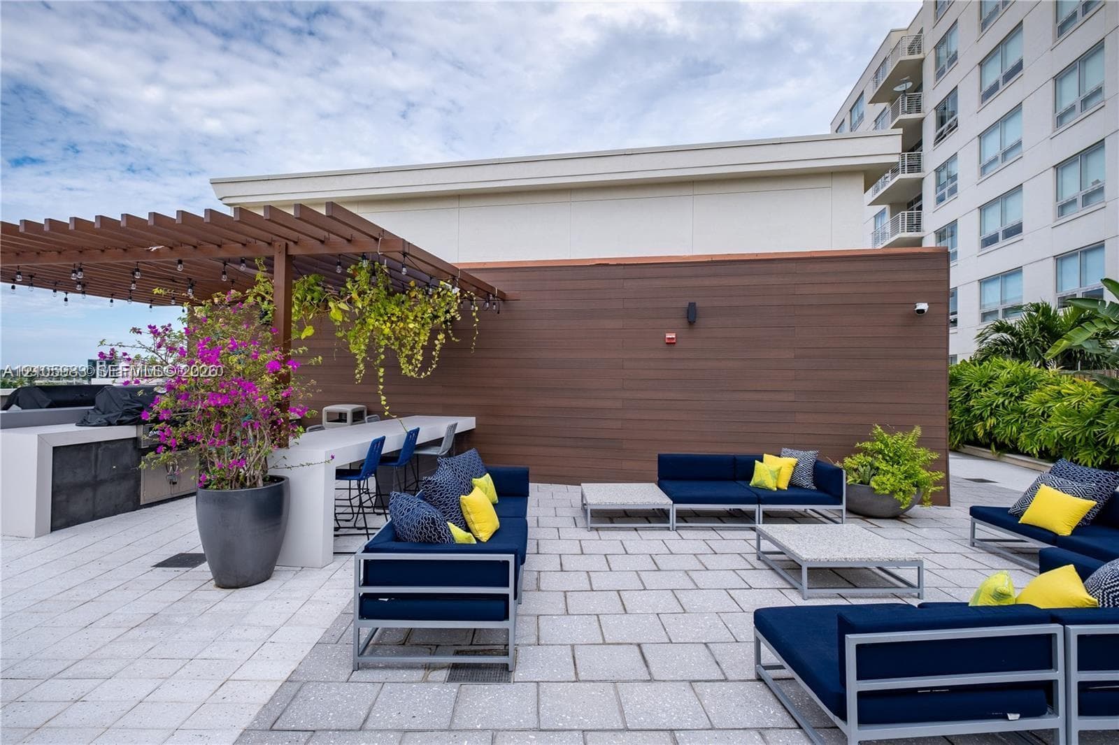 Rooftop terrace featuring a stone paver floor, built-in outdoor kitchen with a service counter, and a wooden pergola structure with integrated string lighting