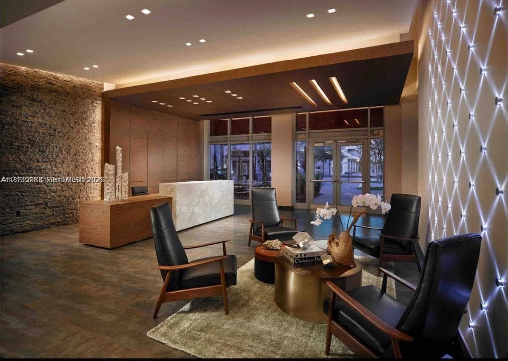 Stone-clad accent wall, custom built-in reception desk with stone facade, coffered wood-finish ceiling, recessed lighting, and geometric wall-mounted accent lighting