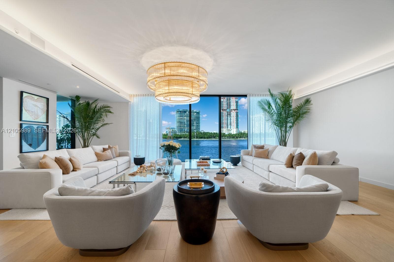 Open-concept living space featuring wood-finish flooring, recessed perimeter ceiling lighting, a tiered drum chandelier, and expansive floor-to-ceiling windows