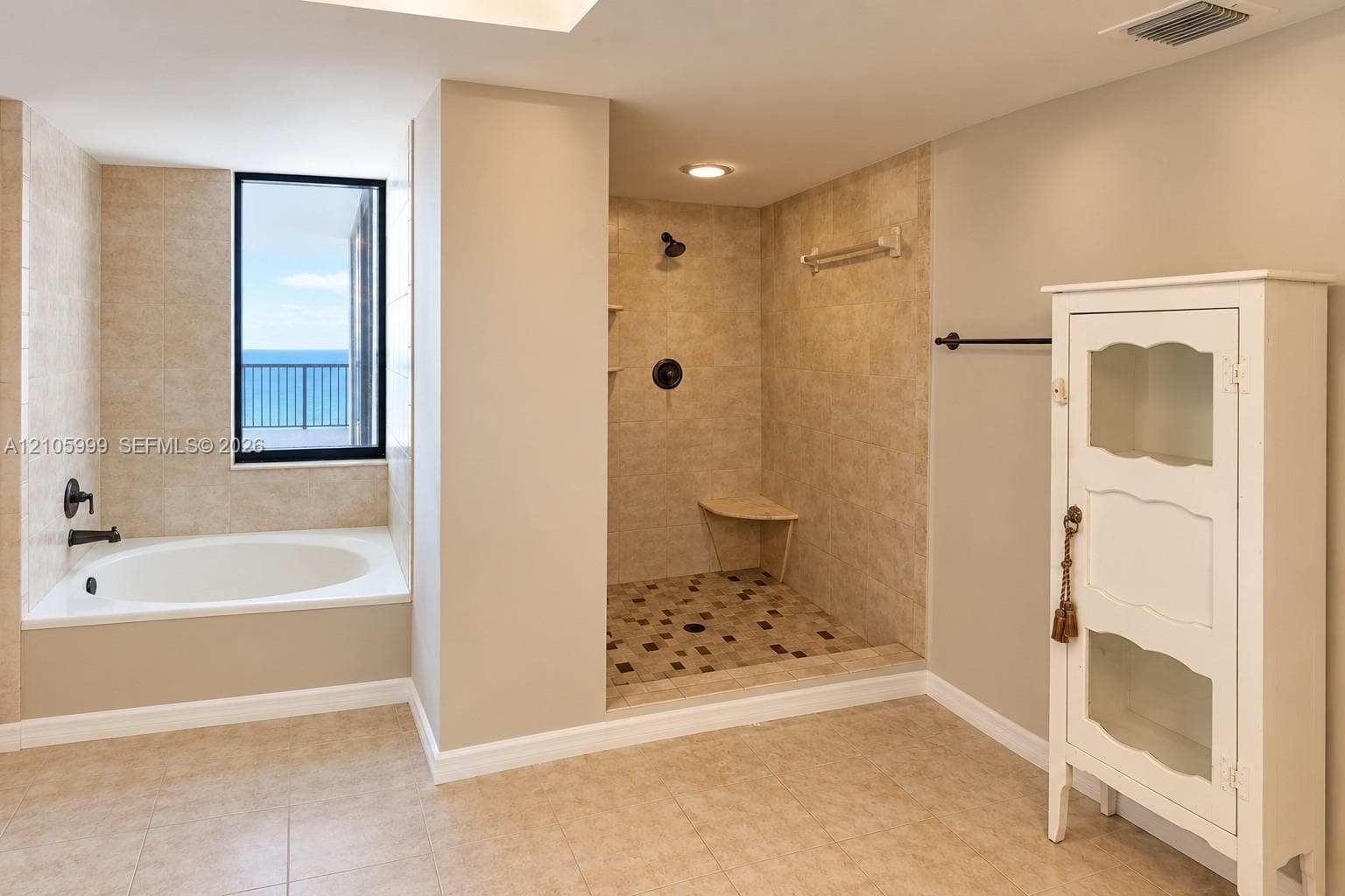 Bathroom featuring a drop-in soaking tub with a deck surround, a walk-in shower with a stone-tile floor and built-in bench, neutral wall-to-wall ceramic tile, and matte black fixtures