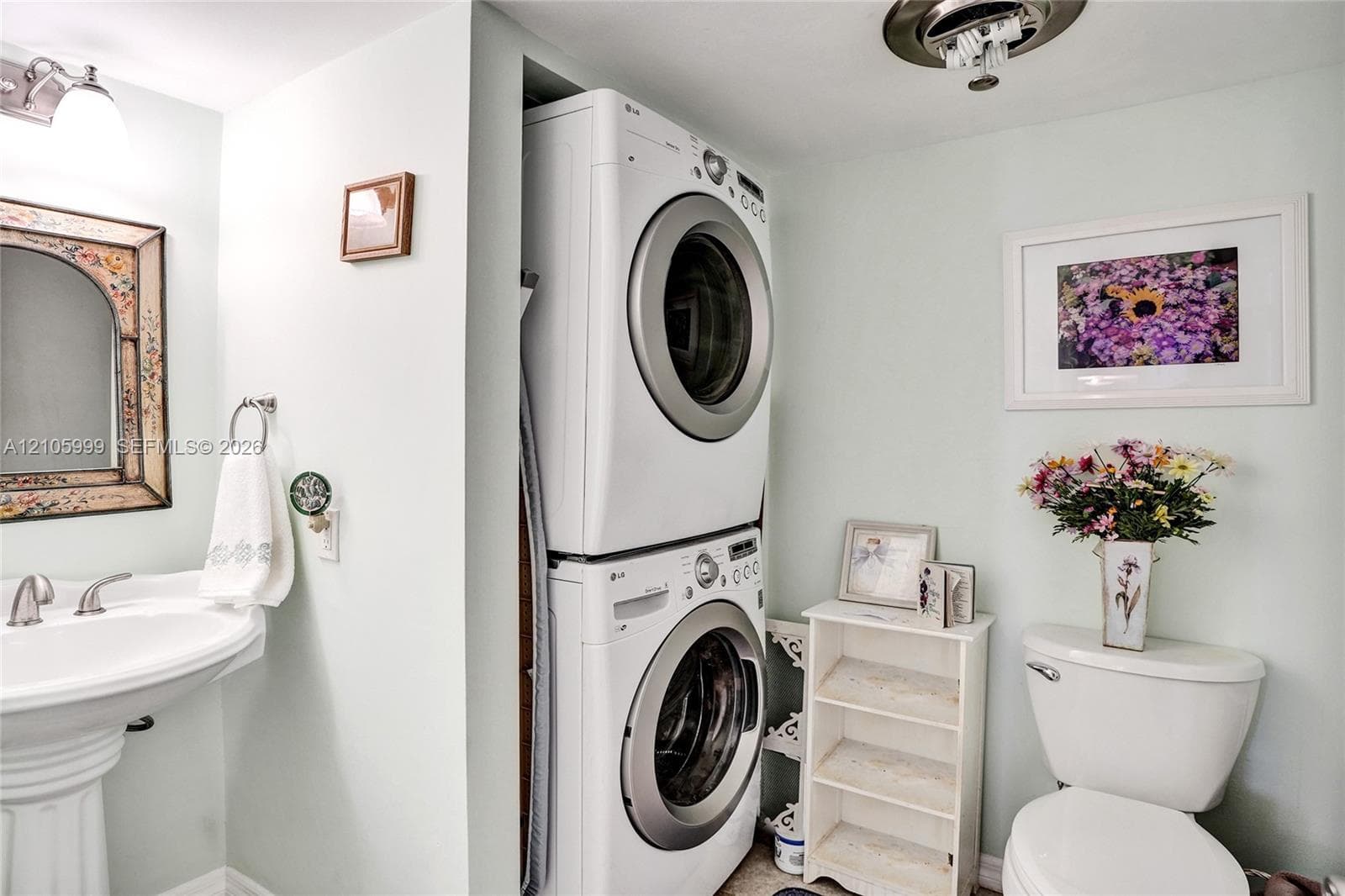Pedestal sink with polished chrome dual-handle faucet, integrated stackable laundry unit, and porcelain toilet