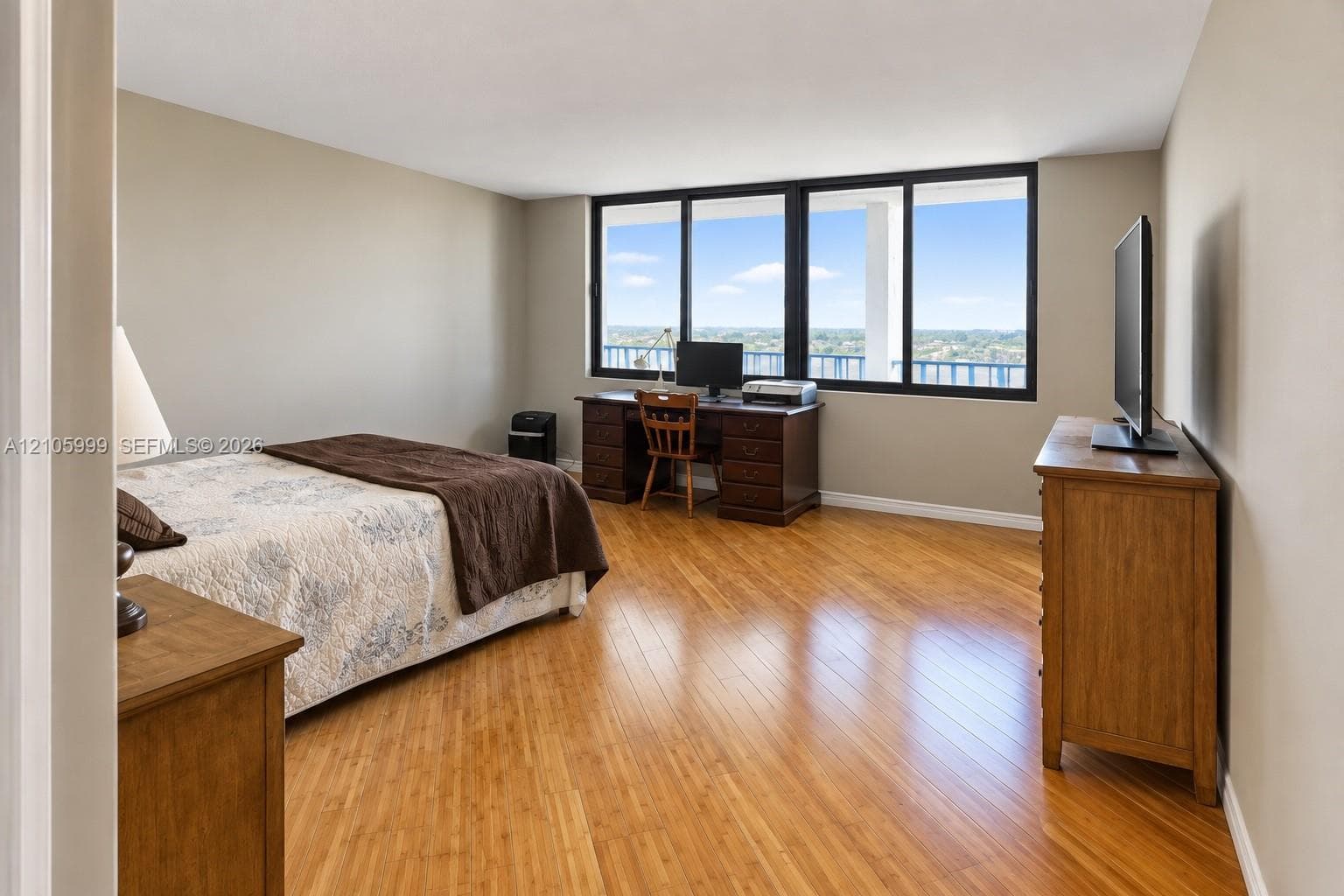 Wood-finish flooring, neutral wall tones, and expansive windows featuring black frames and outdoor scenery