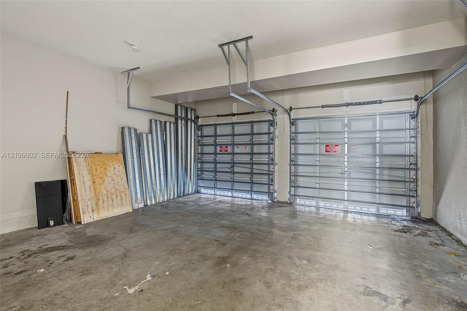 Two-car garage featuring finished concrete flooring, neutral wall paint, and dual metal sectional garage doors with ceiling-mounted operating mechanisms