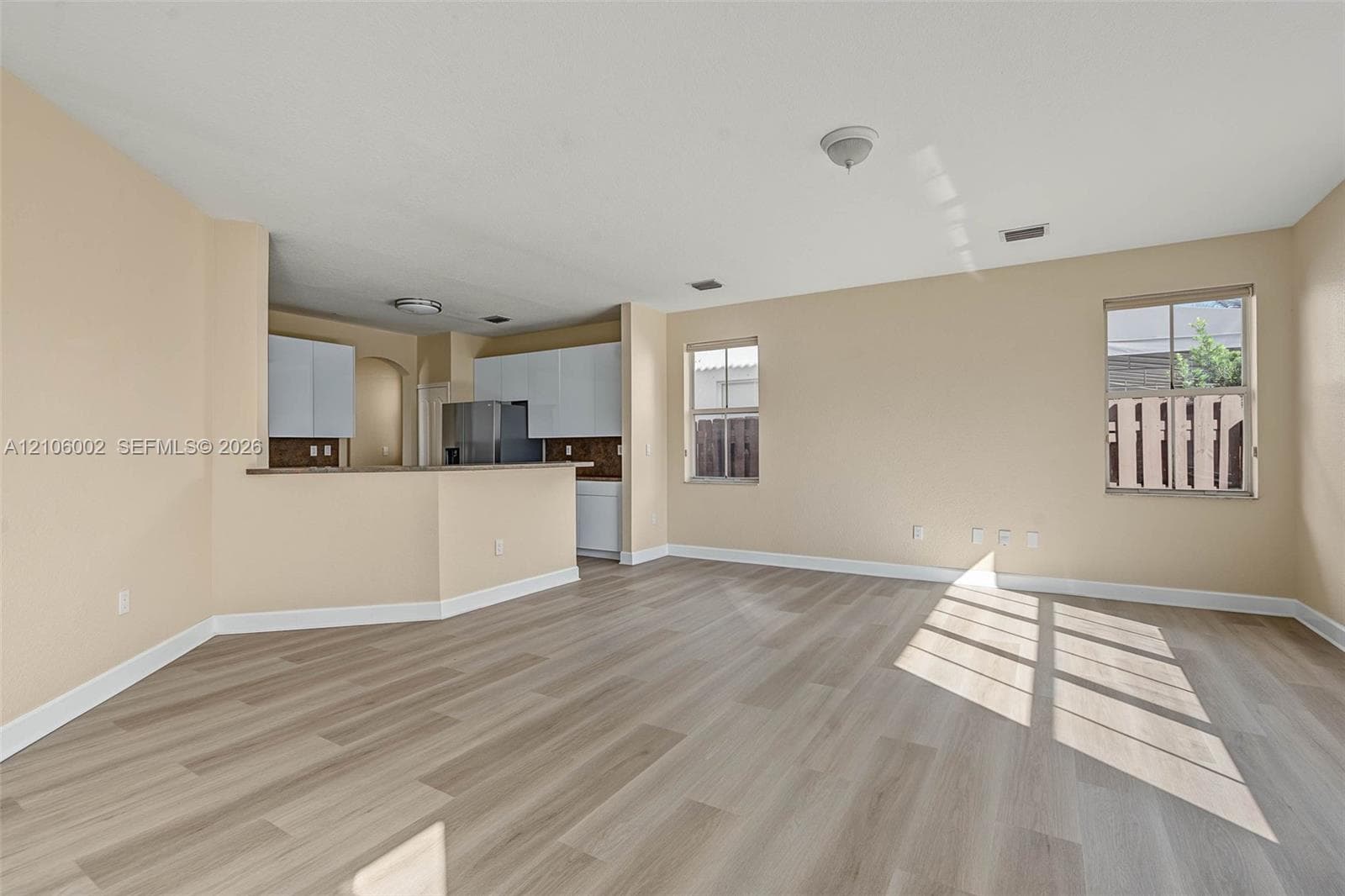 Open-concept space featuring wood-finish flooring, white cabinetry, a kitchen breakfast bar, and multiple windows