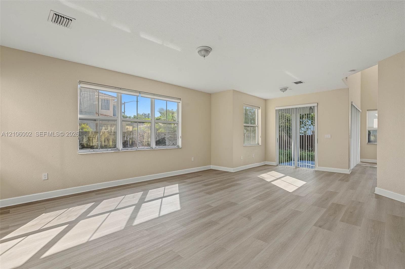 Interior space featuring light-toned wood-finish flooring, large multi-pane windows, and sliding glass patio doors