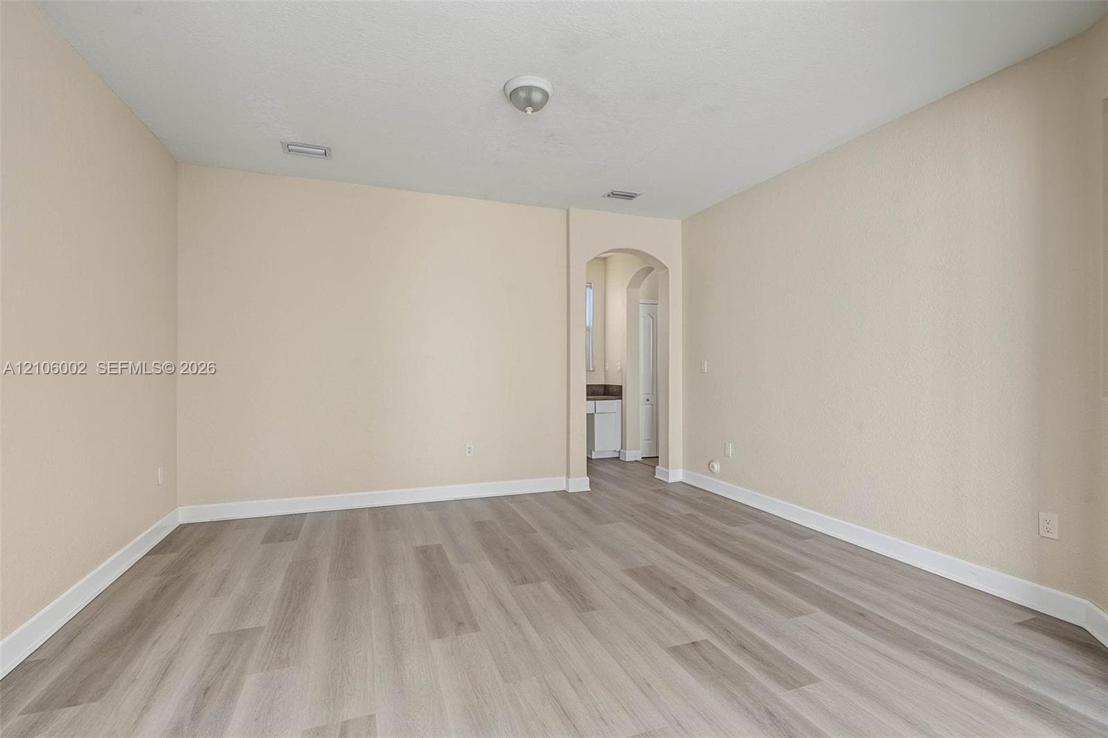 Interior space featuring wood-finish flooring, neutral wall tones, and a structural arched entryway