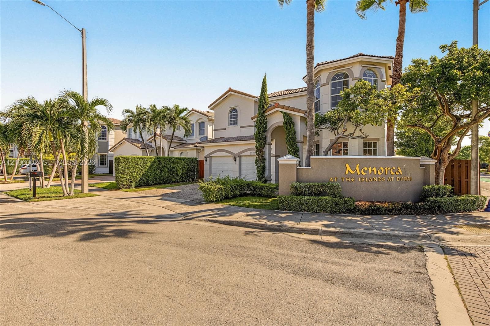 Multi-story stucco exterior featuring arched windows, tile roofing, and a paved driveway