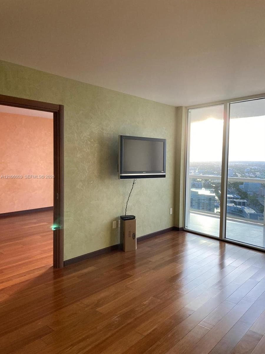 Floor-to-ceiling glass windows, wood-finish flooring, and textured wall finishes