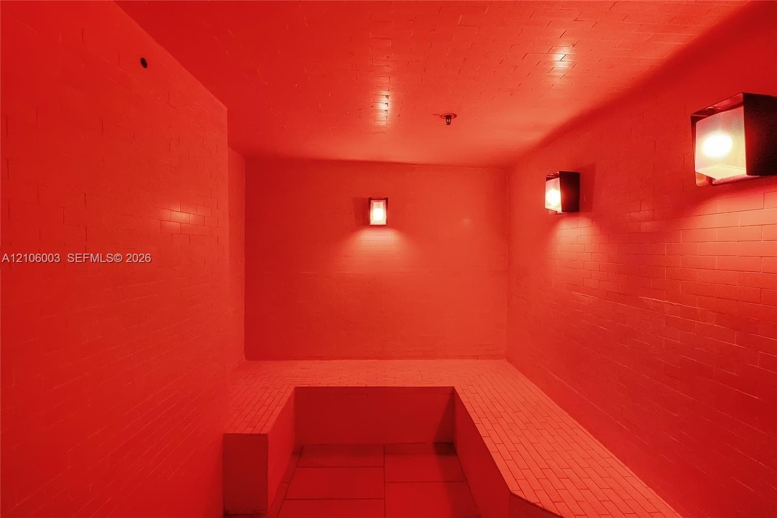 Custom-built sauna featuring floor-to-ceiling masonry, integrated tiled bench seating, and multiple wall-mounted sconces