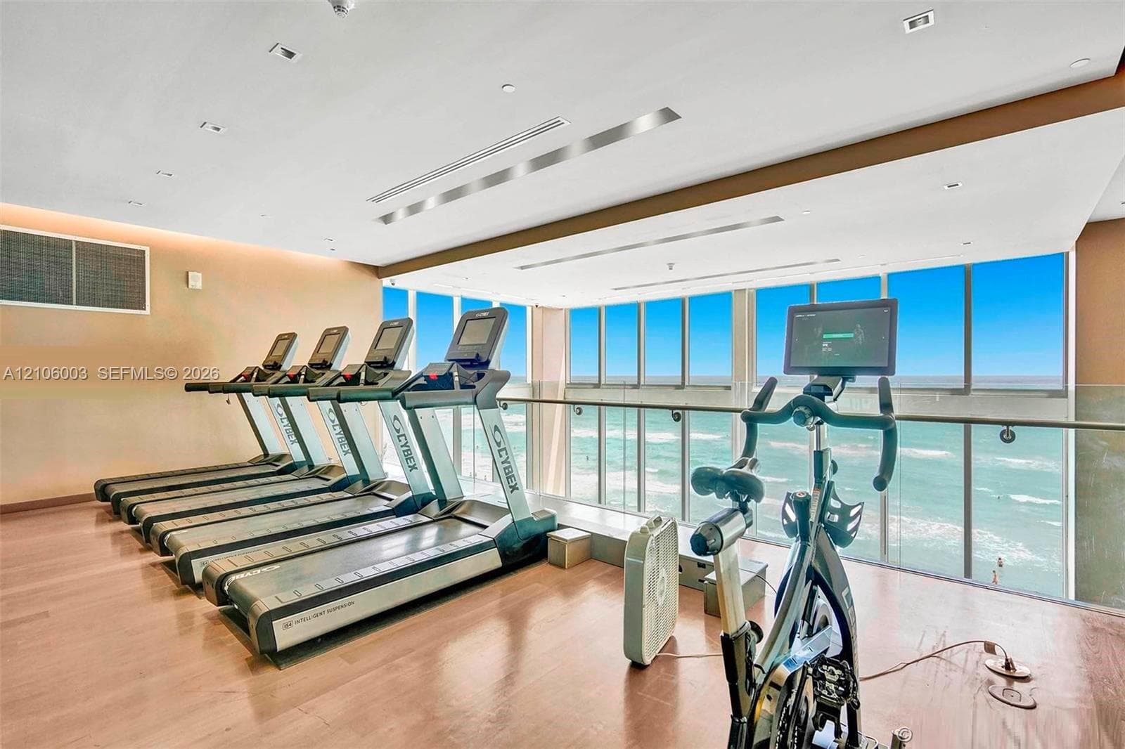 Fitness room featuring floor-to-ceiling windows, wood-finish flooring, recessed lighting, and a glass-paneled railing