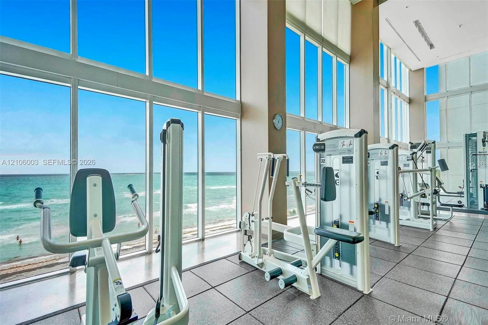 Fitness center featuring floor-to-ceiling windows, high ceilings, ocean scenery, and industrial-grade rubber flooring