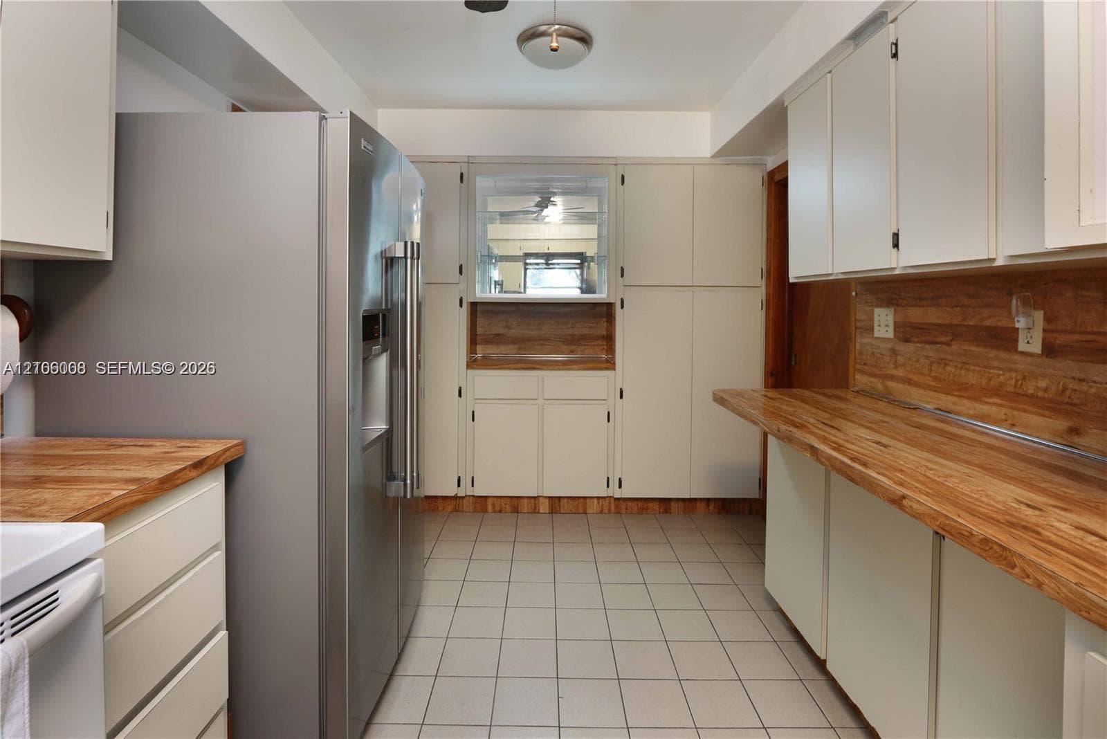 Kitchen featuring wood-finish countertops, stainless steel side-by-side refrigerator, flat-panel cabinetry, and ceramic tile flooring