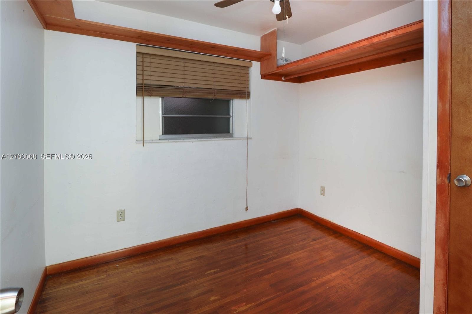Interior space featuring wood-finish flooring, custom wood-trim shelving, and a built-in horizontal window covering