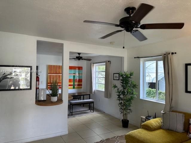Neutral tile flooring, ceiling fans with dark wood-finish blades, and double-pane windows with horizontal muntins, centered around a breakfast bar with a circular wood countertop