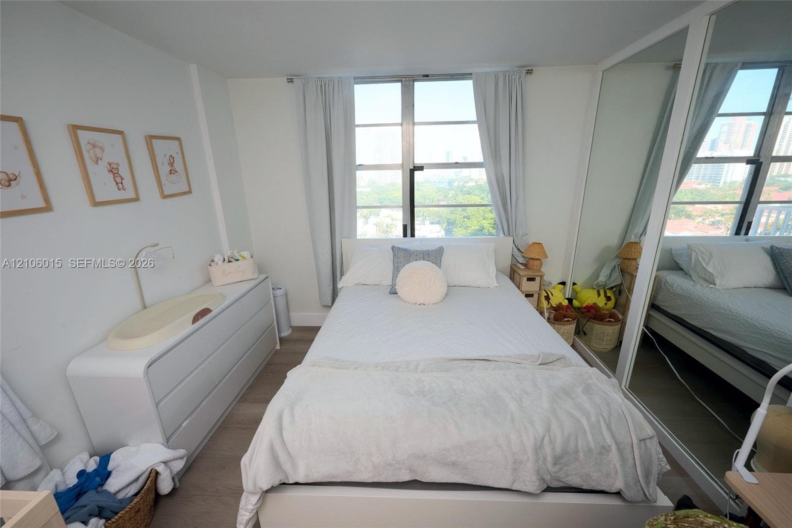 Bedroom featuring wood-finish flooring, large floor-to-ceiling windows, and wall-to-wall mirrored closet doors