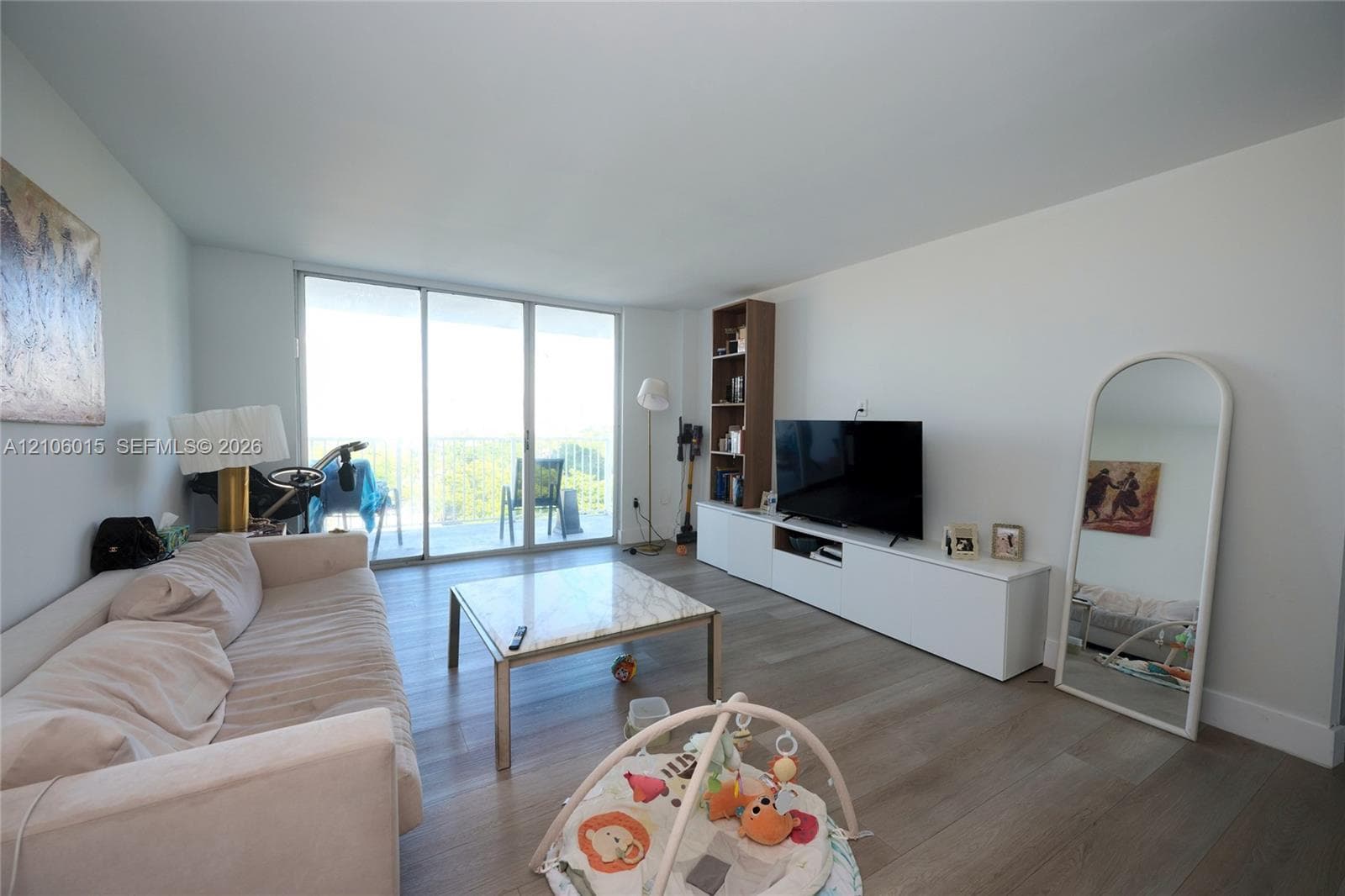 Living area featuring wood-finish flooring, floor-to-ceiling sliding glass doors, and white built-in cabinetry
