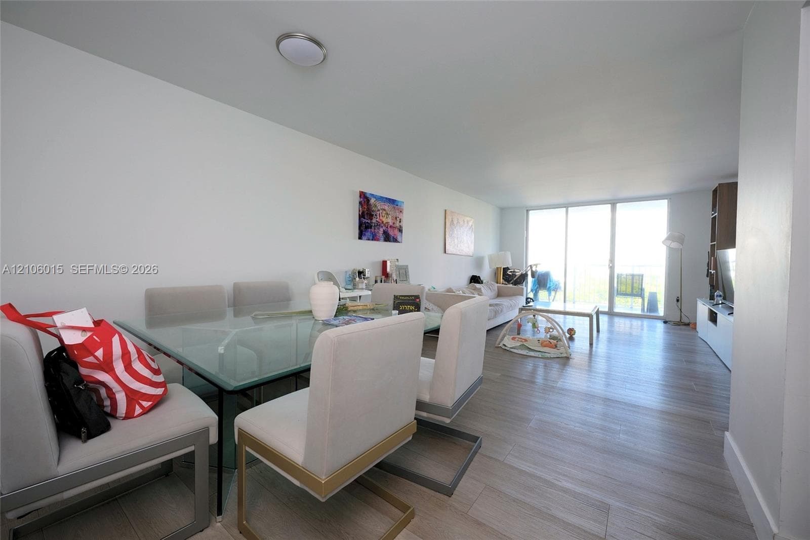 Open-concept interior featuring light wood-finish flooring and large floor-to-ceiling glass doors