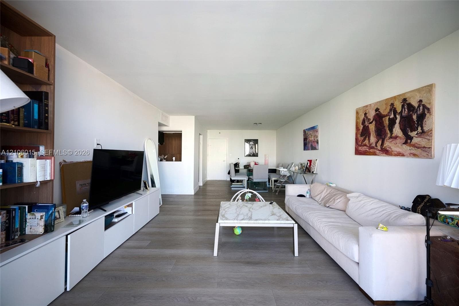 Open-concept living space featuring wood-finish flooring and extensive built-in white cabinetry