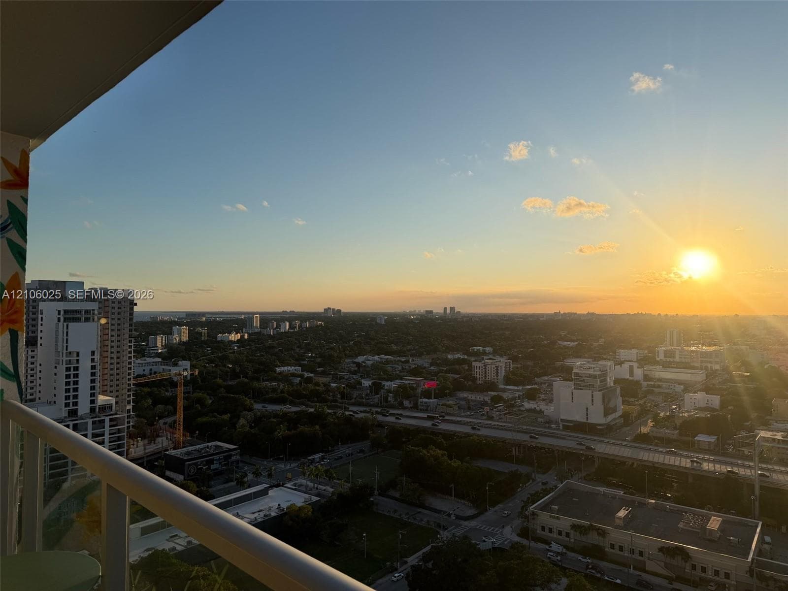 Elevated balcony featuring a white metal railing and sweeping panoramic urban horizon