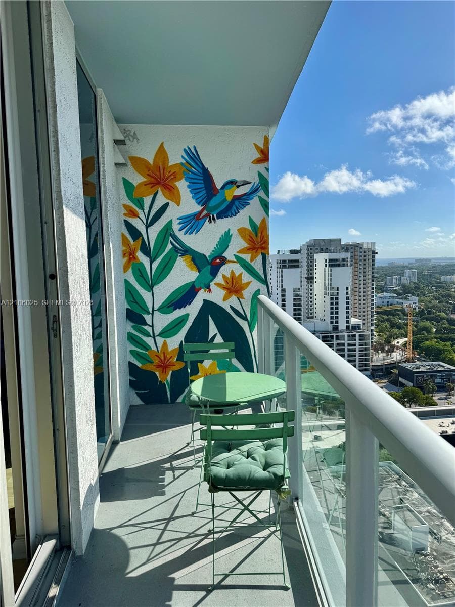 Covered balcony featuring a decorative mural, glass panel railing, and concrete flooring