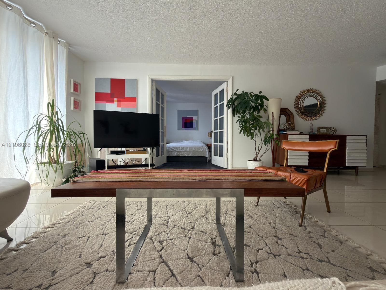 Open living space featuring tile flooring, neutral wall tones, and floor-to-ceiling window coverings
