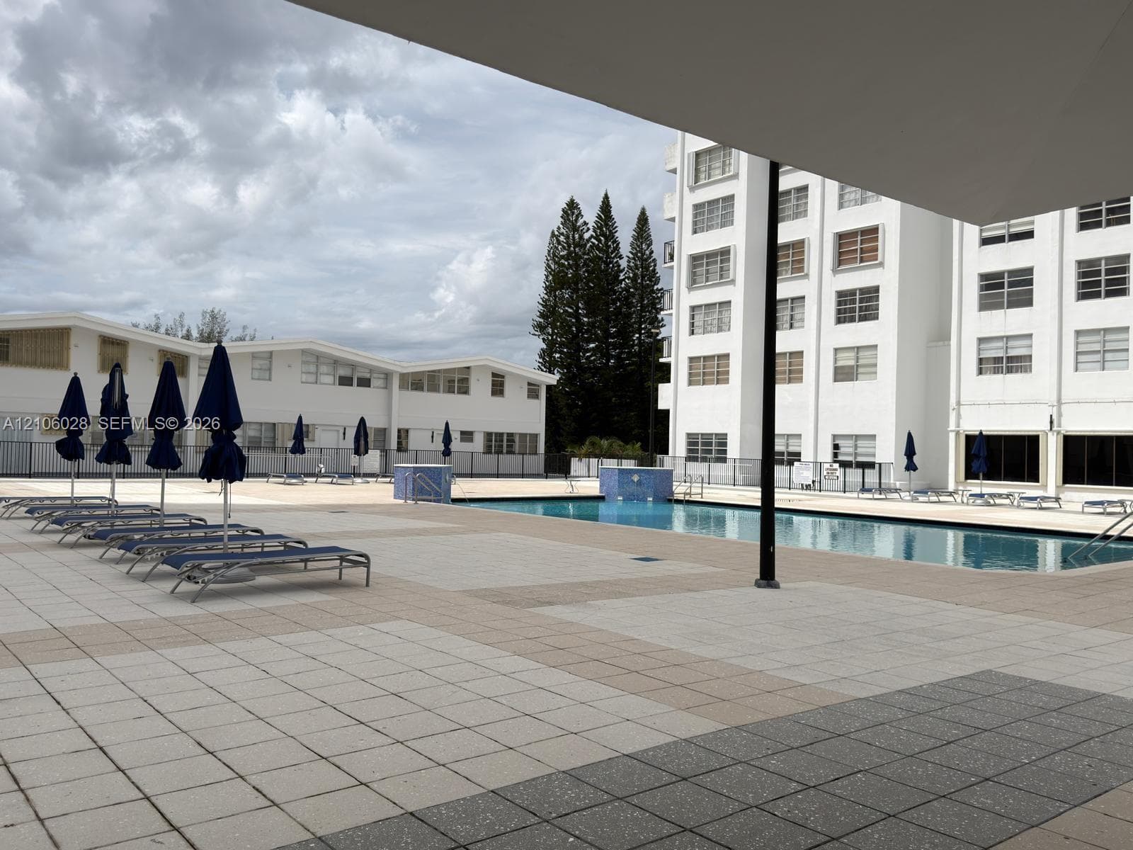 Outdoor swimming pool area featuring a rectangular basin with tile deck surround and metal perimeter fencing