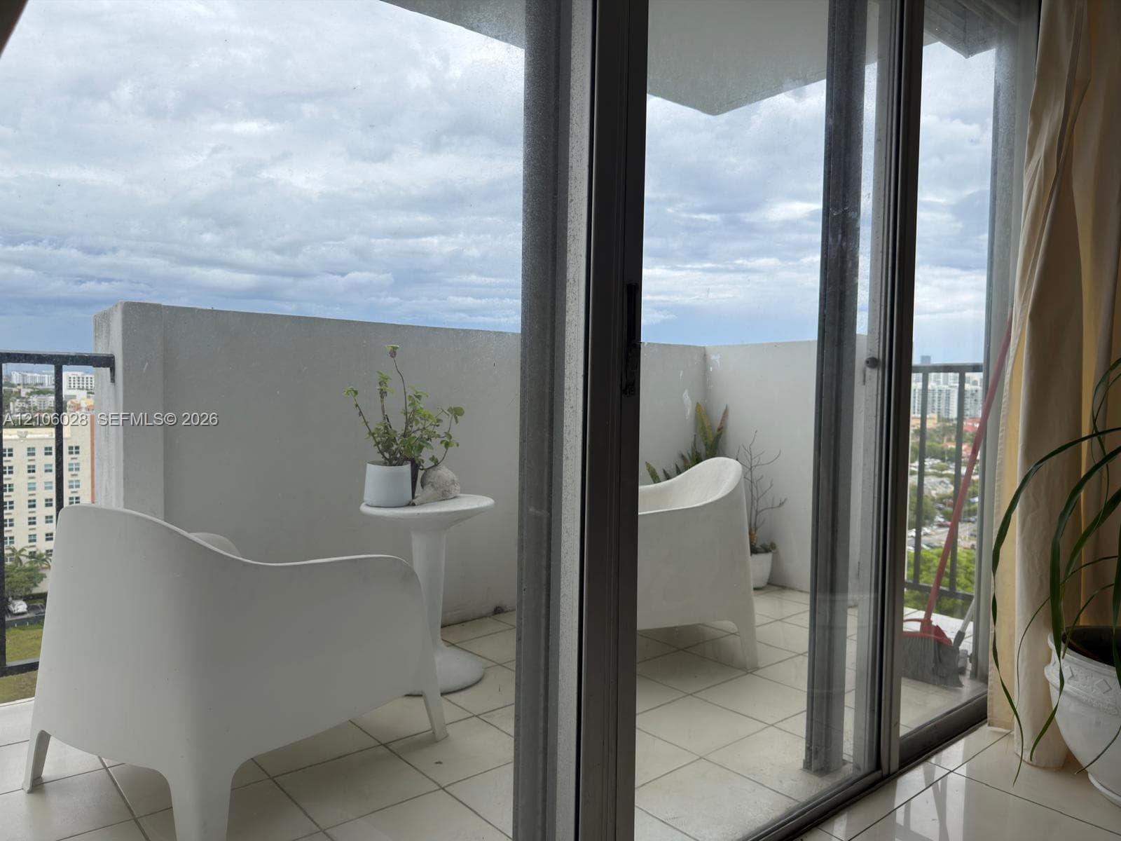 Private balcony featuring ceramic tile flooring, solid concrete perimeter walls, and sliding glass entry doors