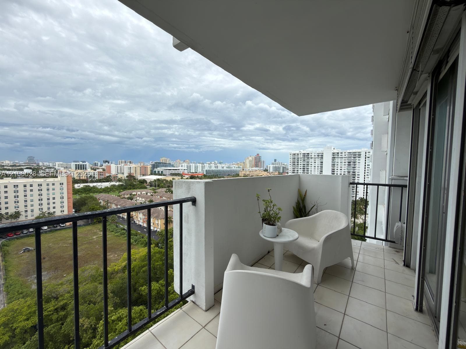 Covered balcony featuring white tiled flooring and black metal railing