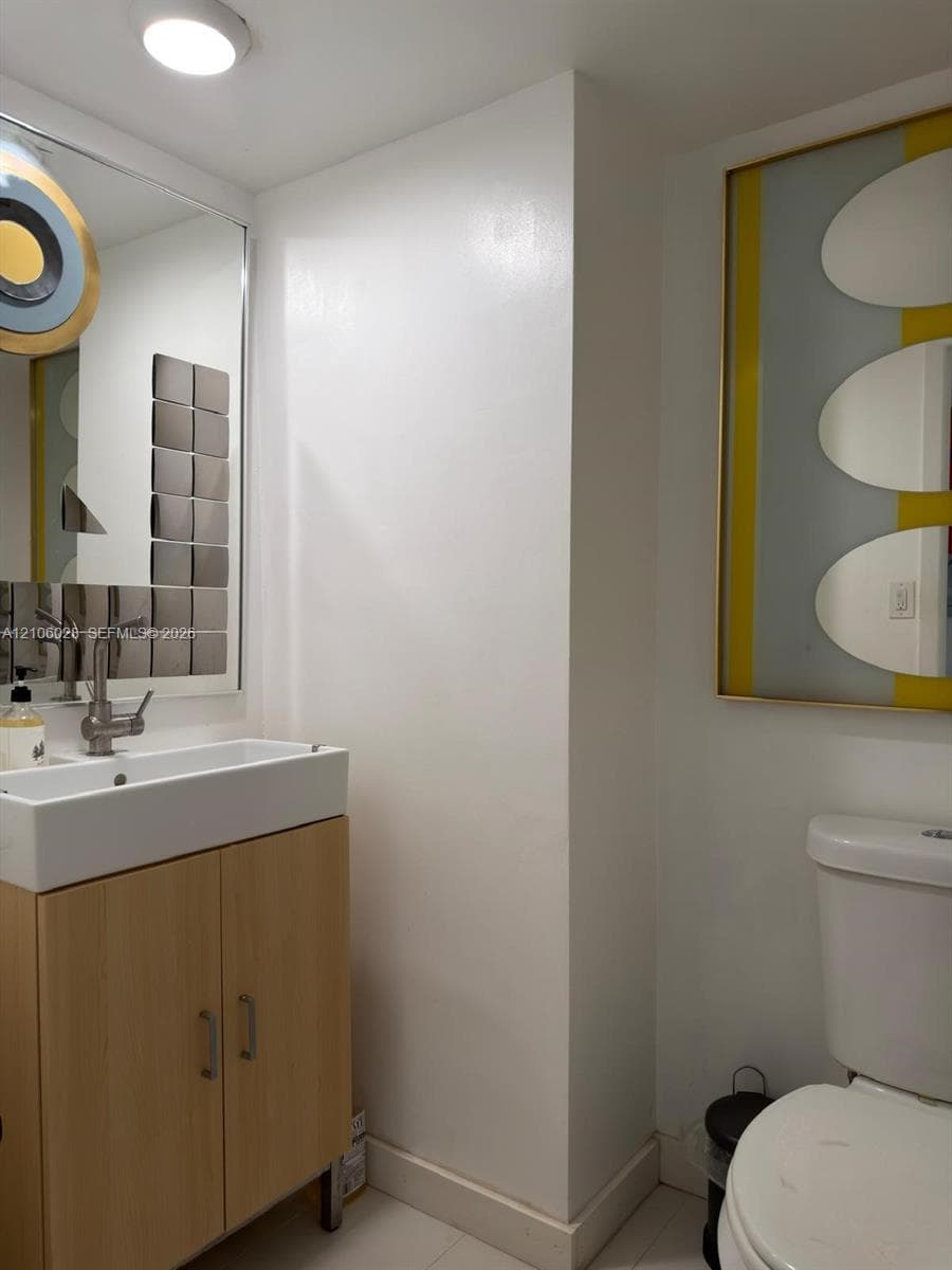 Bathroom featuring a light-wood vanity cabinet, rectangular ceramic vessel sink, sleek metallic faucet, and a large wall-mounted mirror