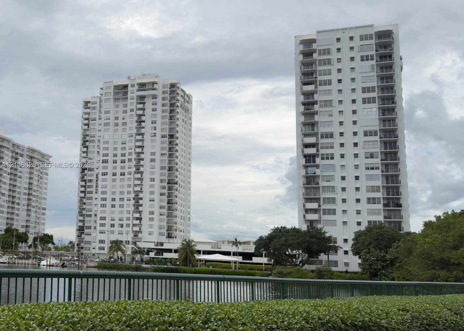 High-rise residential towers featuring multiple private balconies, floor-to-ceiling windows, waterfront positioning, and landscaped perimeter greenery