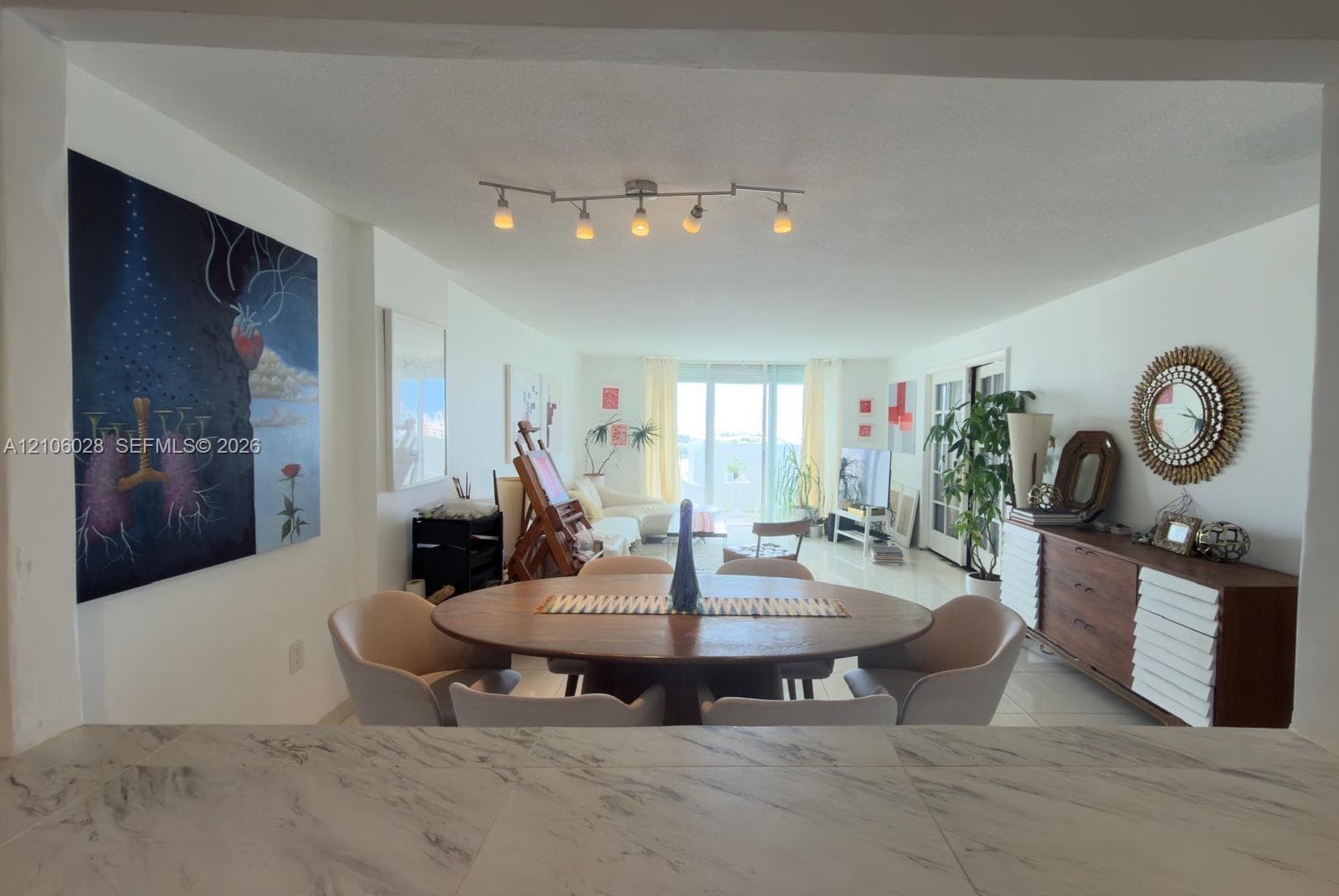 Open-concept area featuring stone-finish countertop, polished tile flooring, and multi-directional track lighting