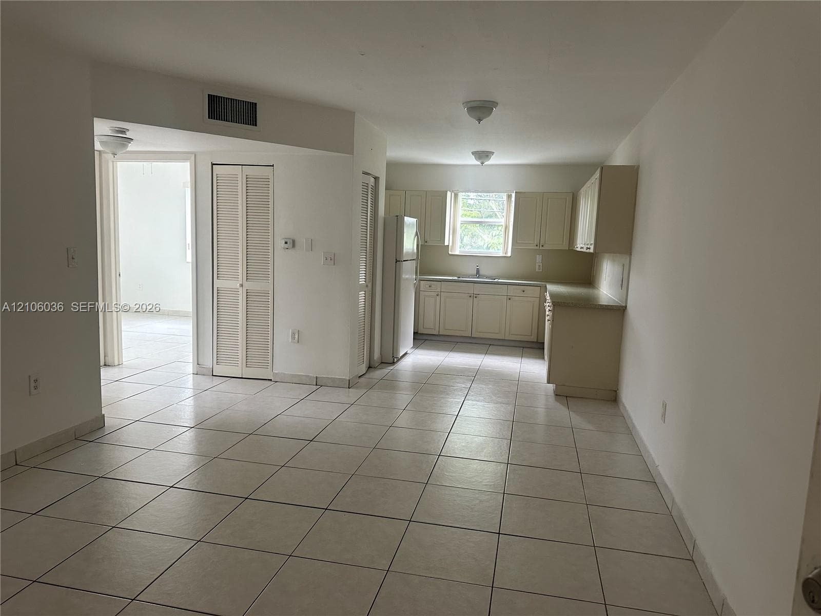 Kitchen featuring cabinetry with neutral finish, tile flooring, and integrated white appliances