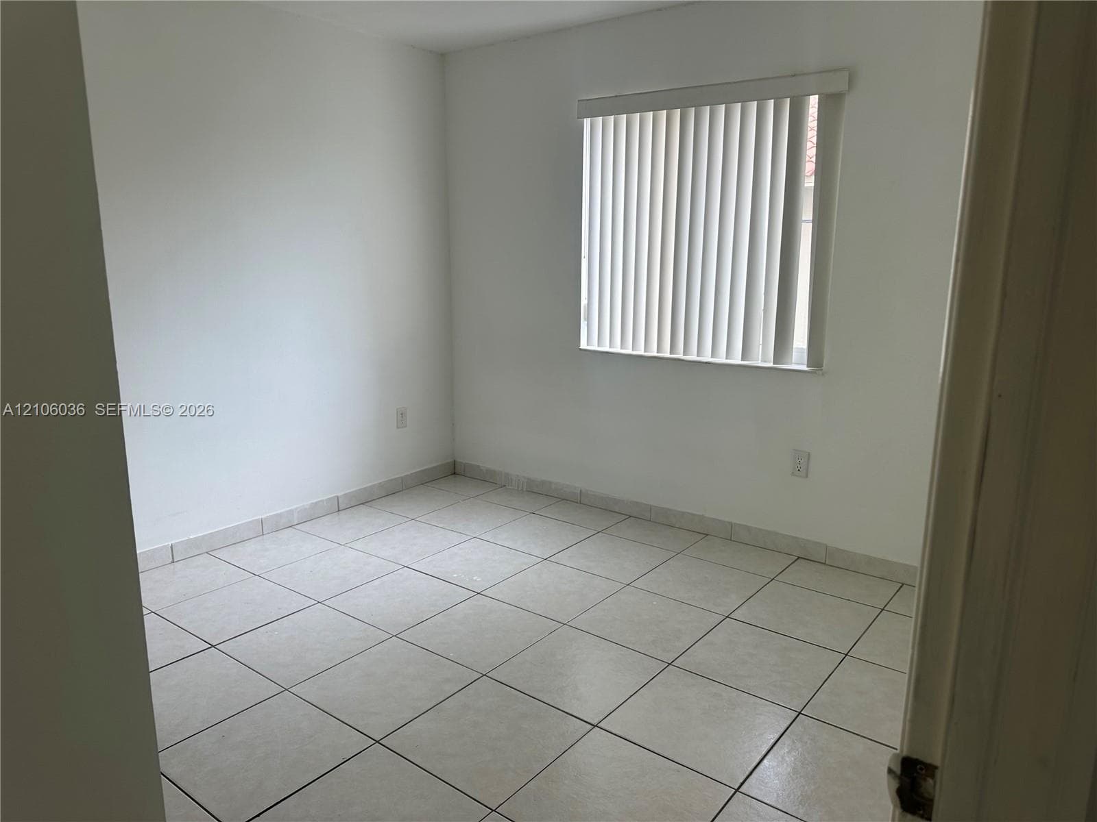 Neutral interior featuring light-colored square tile flooring and vertical blinds