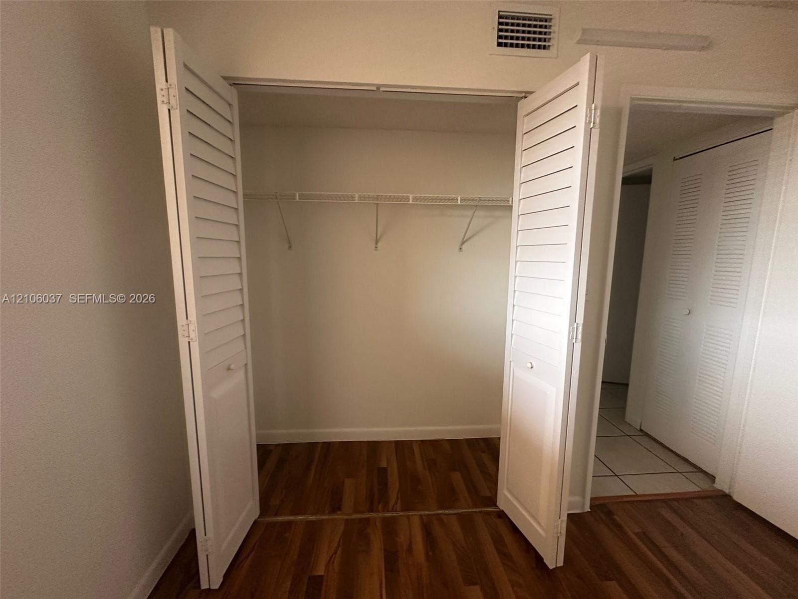 Closet featuring white louvered bifold doors, wood-finish flooring, and integrated wire shelving