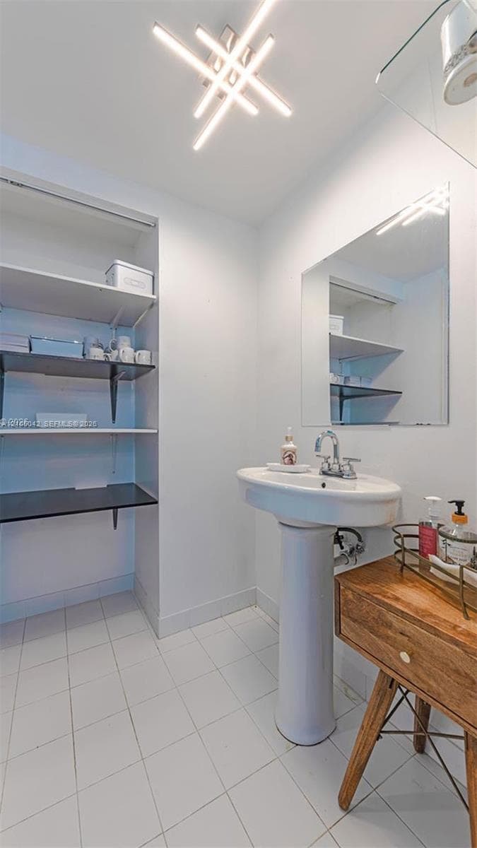 Pedestal sink with chrome faucet, built-in recessed shelving, wall-mounted mirror, and geometric linear light fixture