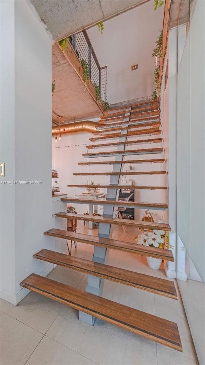 Open-riser staircase featuring wood treads, a central steel spine, and cable railing