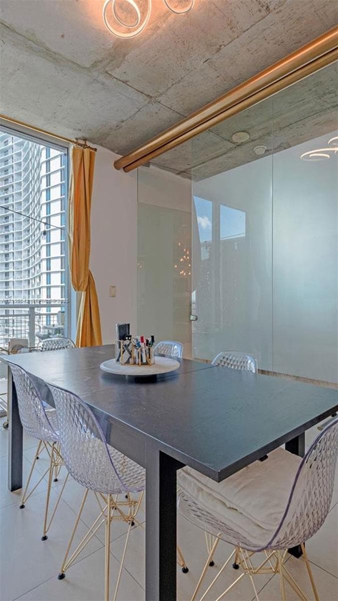 Modern workspace featuring a sleek black work surface, wire-frame seating, exposed concrete ceiling with integrated neon accent lighting, and floor-to-ceiling frosted glass partition